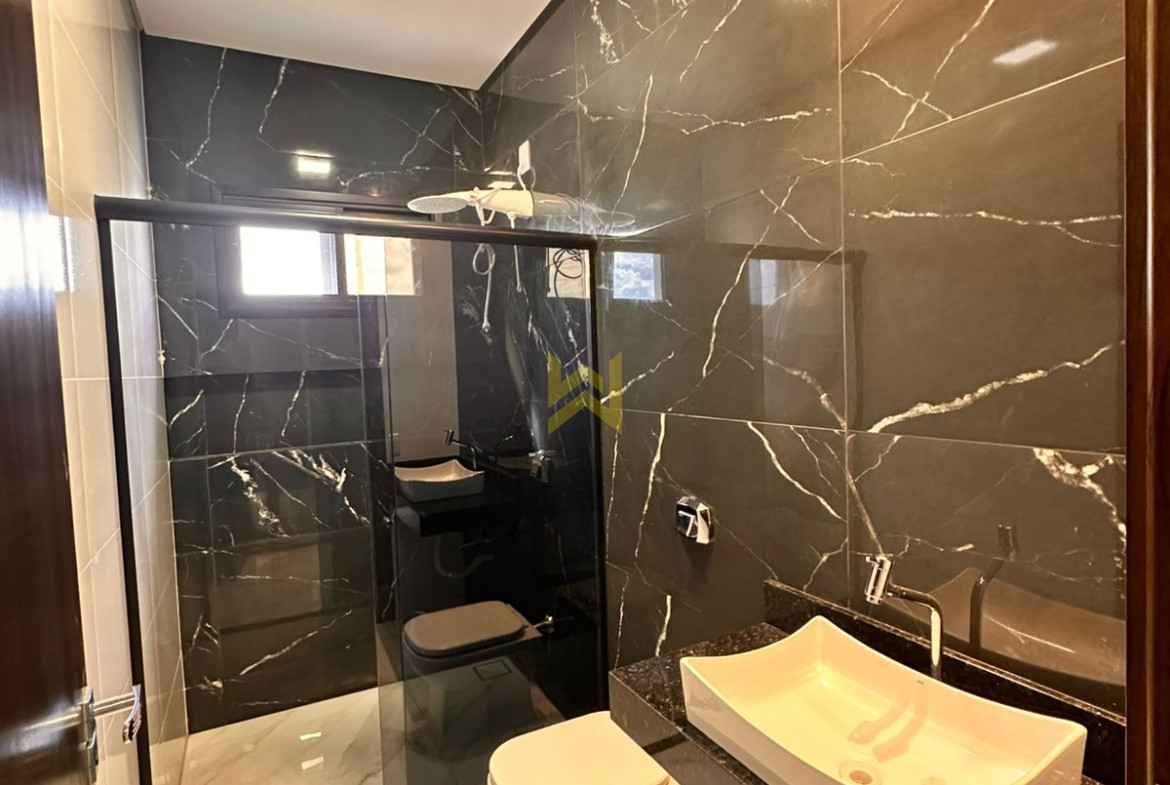 Banheiro com revestimento escuro e bancada de granito, estilo sofisticado — imóvel em Vilhena - RO.