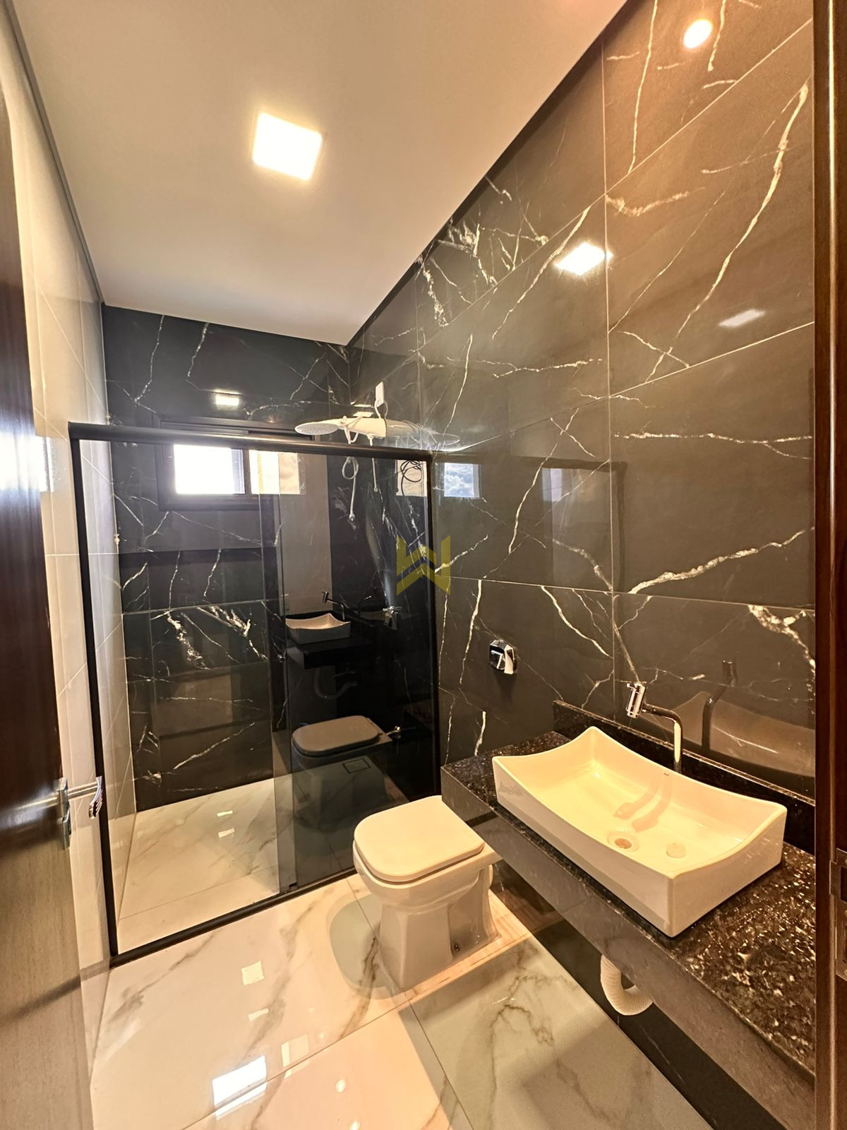 Banheiro com revestimento escuro e bancada de granito Vilhena RO Banheiro com revestimento escuro e bancada de granito, estilo sofisticado — imóvel em Vilhena - RO.