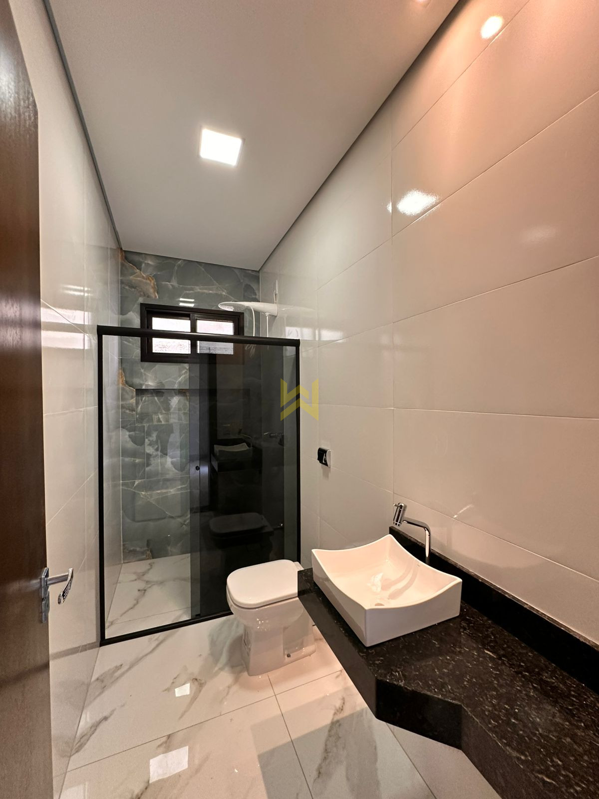 Banheiro moderno em Vilhena – Wender Imóveis Banheiro moderno em imóvel à venda em Vilhena - RO, com revestimento marmorizado e bancada em granito — Wender Imóveis.