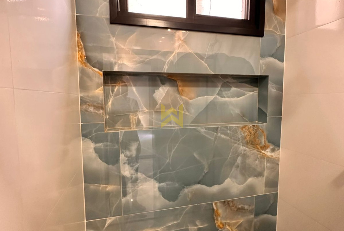 Banheiro moderno em imóvel à venda em Vilhena - RO, com revestimento marmorizado e bancada em granito — Wender Imóveis.