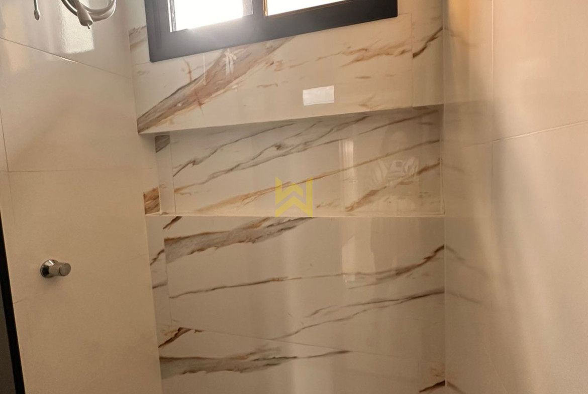 Banheiro moderno em imóvel à venda em Vilhena - RO, com revestimento marmorizado e bancada em granito — Wender Imóveis.